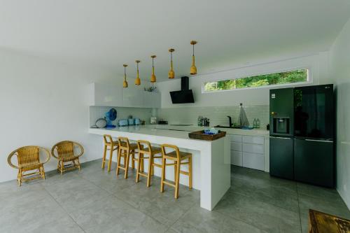 a kitchen with white cabinets and a counter with chairs at KPG Suite Dream in Ban Nua