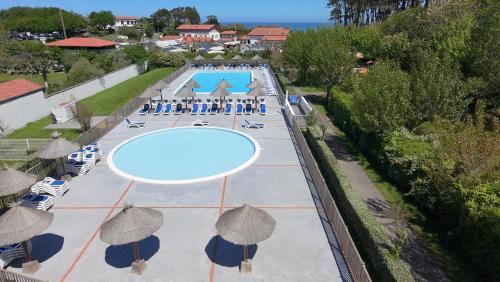 une vue aérienne d'une piscine avec des parasols dans l'établissement Pause Luzienne à deux pas de la plage, à Saint-Jean-de-Luz