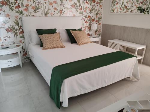 a bedroom with a large white bed with green sheets and pillows at DOMUS ULIVI LUXURY ROOMS Nocellara in Catania