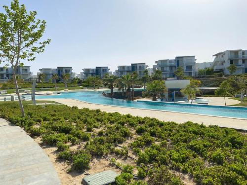 a swimming pool with plants and buildings in the background at Luxury Chalet On The Lagoon Fouka Bay in Marsa Matruh