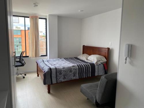 a bedroom with a bed and a chair and a window at Comodo apartamento in Tunja