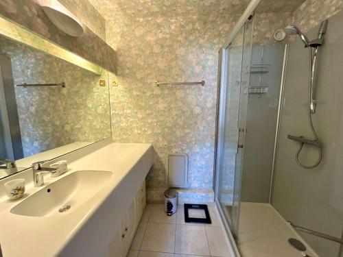 La salle de bains est pourvue d'un lavabo et d'une douche avec une porte en verre. dans l'établissement Spacieux Appartement T3 avec Terrasse Ensoleillée et Parking - FR-1-494-211, à Royan