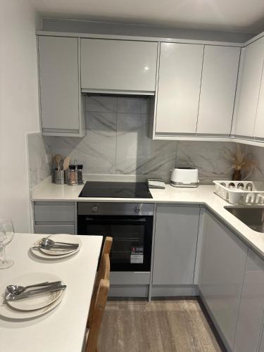 a kitchen with white cabinets and a stove top oven at Two Bedroom Flat C in Kentish Town in London