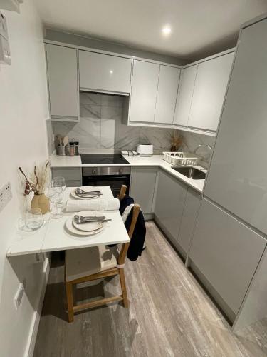 a kitchen with white cabinets and a white table and chairs at Two Bedroom Flat C in Kentish Town in London