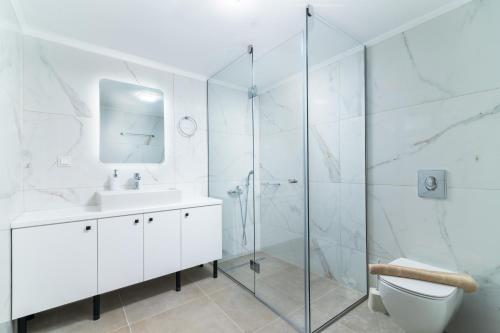 a white bathroom with a sink and a shower at Villa Claire in Andiskárion
