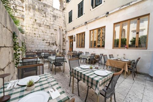 an outdoor restaurant with tables and chairs and windows at Hotel Peristil in Split
