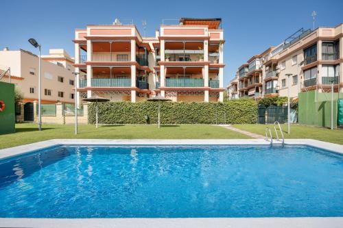 an apartment with a swimming pool in front of a building at Camaleón 7 in Chipiona