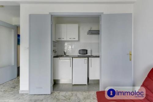 une cuisine avec des armoires blanches et un comptoir dans l'établissement Air-conditioned studio near the Promenade des Anglais, à Nice