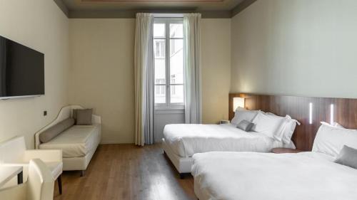 a hotel room with two beds and a couch at I Portici Hotel Bologna in Bologna