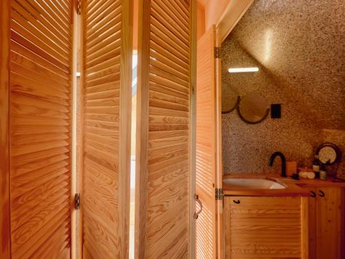 a wooden shower door in a bathroom with a sink at CAMPY ECO HOUSE • EGER in Egerszólát