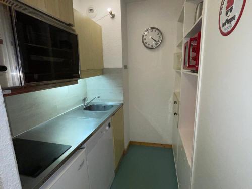 une cuisine avec un évier et une horloge murale dans l'établissement Studio lumineux avec balcon, proche des pistes - FR-1-181-2645, à La Plagne Tarentaise