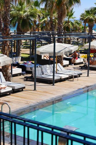 a pool with chaise lounges and umbrellas next to a resort at Ayvalık Sea Long in Ayvalık