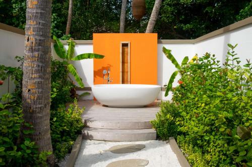 a bath tub sitting on top of a wooden walkway at Angsana Velavaru in Dhaalu Atoll
