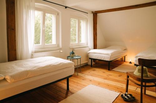 a bedroom with two beds and two windows at NONNA Hof - Natur & Ruhe in Ostseenähe in Altwigshagen