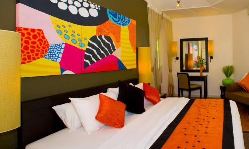 a bedroom with a bed with a large painting on the wall at Angsana Velavaru in Dhaalu Atoll