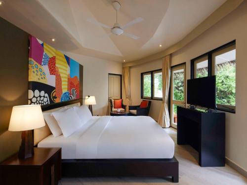 a bedroom with a large white bed and windows at Angsana Velavaru in Dhaalu Atoll