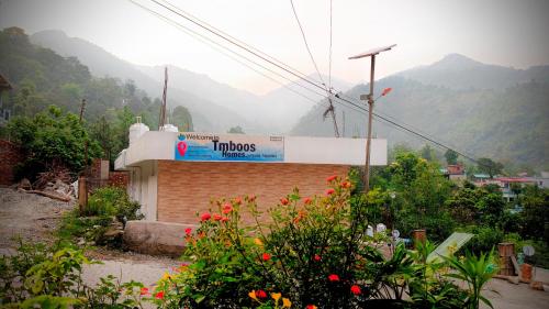 a sign on a building with mountains in the background at Tmboos Homes in Patwa Dunga