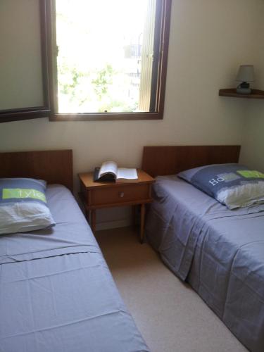 une chambre avec deux lits, un bureau et une fenêtre dans l'établissement apt t2 100 m de la plage et a l oree de la foret, à Saint-Georges-de-Didonne