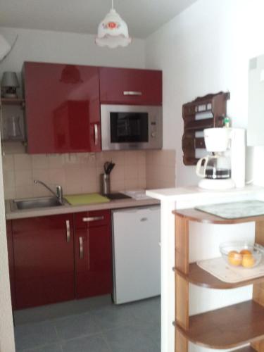 une cuisine avec des armoires rouges et un évier dans l'établissement apt t2 100 m de la plage et a l oree de la foret, à Saint-Georges-de-Didonne