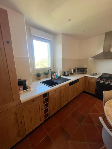 une cuisine avec des armoires en bois, un évier et une fenêtre dans l'établissement Casa Dume, à Calenzana