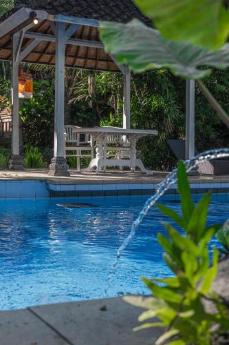 a swimming pool with a table and a gazebo at Eiwa House in Ubud