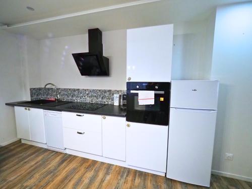 a kitchen with white cabinets and a black counter top at La Marine by Leslodgespa - Appartement moderne et équipé au style marin, proche de Bâle et de l'aéroport in Hésingue