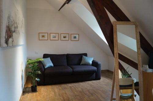 a living room with a black couch in a attic at ART Hôtel in Kaysersberg
