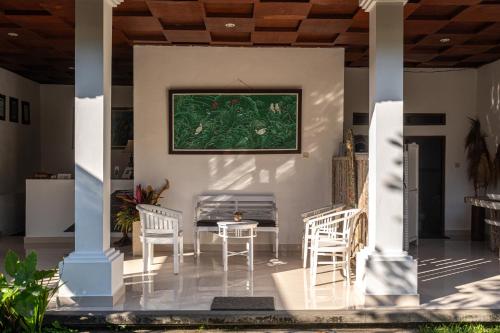 a patio with chairs and a table and a painting on the wall at Eiwa House in Ubud