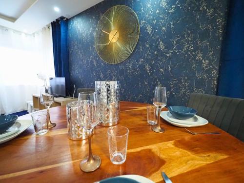 a table with glasses and plates and a fan on the wall at La Marine by Leslodgespa - Appartement moderne et équipé au style marin, proche de Bâle et de l'aéroport in Hésingue