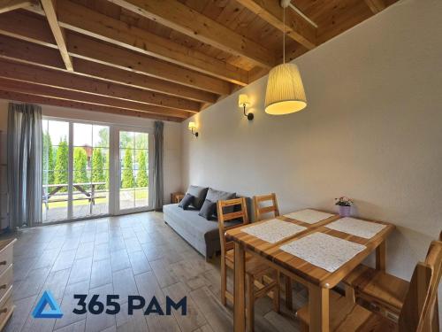 a living room with a table and a couch at 365PAM - Urocze Domki Letniskowe blisko morza in Bobolin