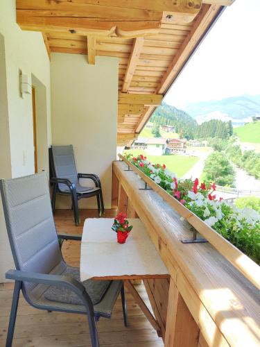 a balcony with a table and chairs and flowers at Haus Enzian in Mittersill