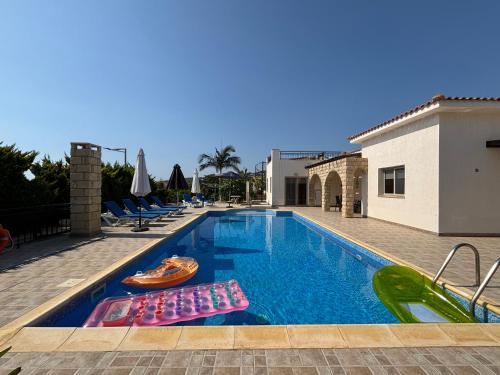 a swimming pool with lounge chairs in a resort at Villa Imperial Sea-Caves Private Pool in Peyia