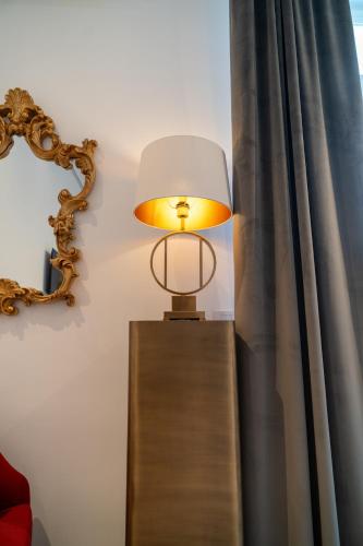 a lamp on a wooden table next to a curtain at La Corte di Partenope Luxury Suite in Naples