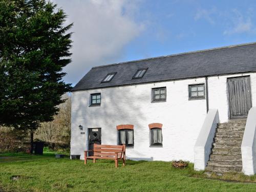 a white house with a bench in front of it at Dilys - 19076 in Carew