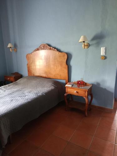 a bedroom with a bed with a wooden headboard and a table at Casa rural Finca Galapero in Alcántara