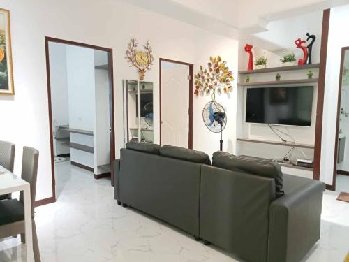 a living room with a couch and a flat screen tv at Spacious Fully Furnished 2BR Condo in Mactan in Sudtungan