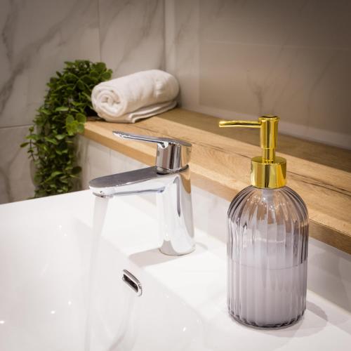 a bathroom sink with a soap dispenser on it at Stylish Manchester City Escape - Walk to Chinatown in Manchester