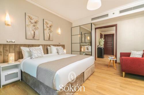 a bedroom with a large bed and a red chair at Sokon Residence Partial Nile view at Maadi in Cairo