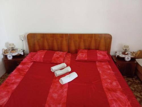 a red bed with two white towels on it at Rustic house Hutovo Blato in Čapljina