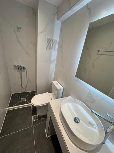 a white bathroom with a sink and a toilet at Pasiphae Hotel in Malia