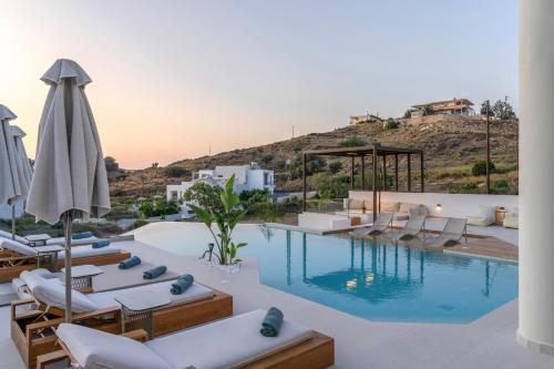 a pool with chairs and an umbrella next to a resort at Luxurious Villa Selestine - With Private Pool in Panormos Rethymno