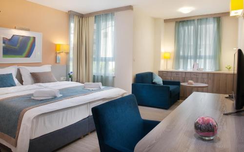a hotel room with a large bed and blue chairs at Guesthouse Aroma in Makarska