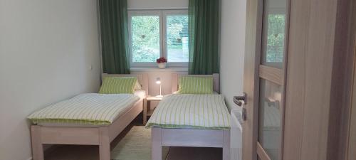 2 łóżka w małym pokoju z zielonymi zasłonami w obiekcie Apartmány U Špilínků-lipensko w mieście Horní Planá