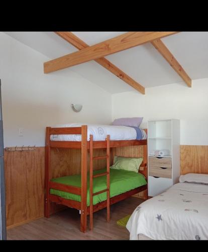 a bedroom with two bunk beds with a green seat at Ruta 7 in Coihaique