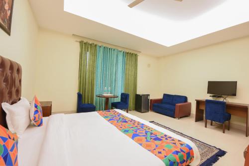 a hotel room with a bed and chairs and a television at FabHotel AM Bliss in Gurgaon