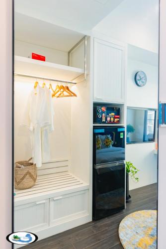 a white kitchen with a refrigerator and a clock at Oscar Seaview Apartment in Phu Quoc