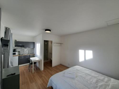 une chambre blanche avec un lit et une cuisine dans l'établissement Florence - Appart'city, à Reims
