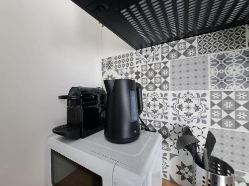 - une cafetière sur un comptoir dans une cuisine revêtue de carrelage dans l'établissement Florence - Appart'city, à Reims