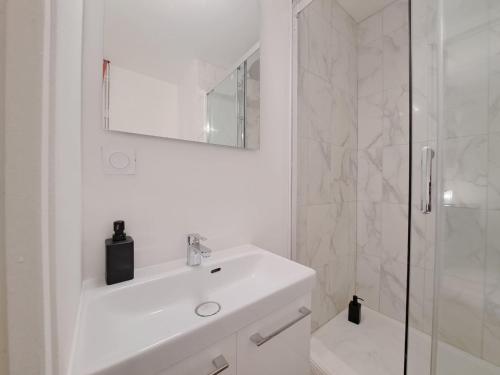 une salle de bain blanche avec un lavabo et une douche dans l'établissement Florence - Appart'city, à Reims