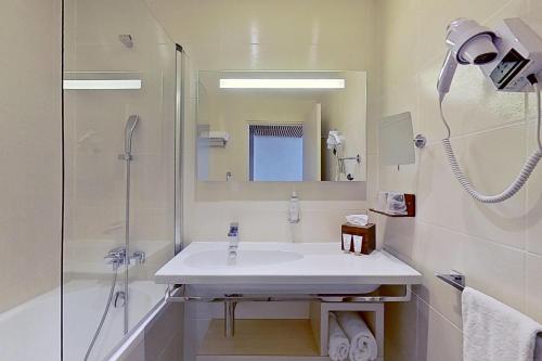 a white bathroom with a sink and a shower at Aquabella Hôtel & Spa in Aix-en-Provence